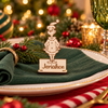 A personalized wooden Grinch place card holder with the name 'Jeremiah' engraved, styled on a dark green napkin over a white plate with gold trim, set against a festive Christmas background with lights and ornaments.