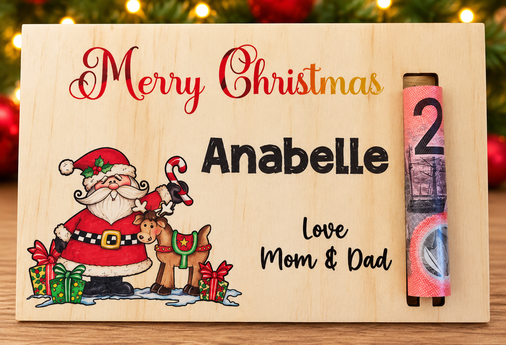 Personalized wooden Christmas advent calendar for Mom & Dad, engraved with 'Merry Christmas', the name 'Anabelle', and 'Love Mom & Dad', featuring a Santa Claus and reindeer illustration, with a rolled banknote showing the number 2 on the right side.