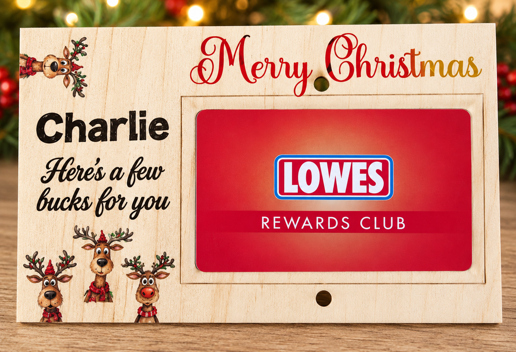 A personalized wooden Christmas gift card holder featuring the text 'Merry Christmas', 'Charlie', and 'Here's a few bucks for you' alongside festive reindeer illustrations. A red Lowes Rewards Club card is displayed in the center slot, set against a blurred holiday background.