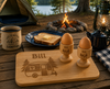 Personalised camping breakfast set featuring a custom engraved bamboo chopping board and matching egg cup, perfect for caravans, camping trips and outdoor adventures.