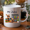 A white ceramic mug with a custom printed design featuring a cartoon kangaroo and the text 'Mr Jules TEACHERS MAKE THE WORLD A BRIGHTER PLACE', set on a wooden table with a blurred background of plants and decor.