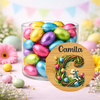 Glass jar filled with colorful Easter eggs and a decorative round sign with 'Camila' on a floral background.