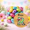 Glass jar filled with colorful Easter eggs and a decorative 'Rose' sign with letter 'R'.