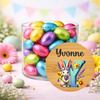 Jar of colorful Easter eggs with a decorative round sign featuring a rabbit and the name 'Yvonne'.