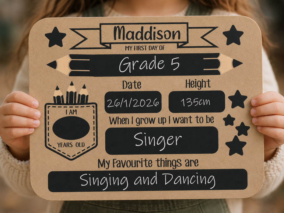 A child holds a personalized sign with school-themed graphics and text, including the name Grade 5, date, height, and aspirations. The sign has a kraft-paper background with black panels, stars, pencil illustrations, and white text.
