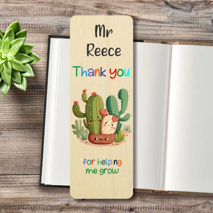 A personalized wooden bookmark styled on an open notebook, featuring a cute cartoon cactus illustration and the text 'Mr Reece Thank you for helping me grow'.