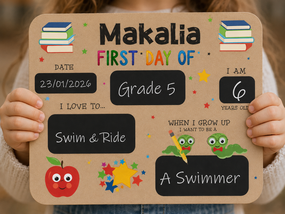 A child holds a personalized sign celebrating their first day of school. The sign features a tan background with black chalkboard-style text boxes and colorful cartoon illustrations, including books, stars, a red apple, and green frogs.