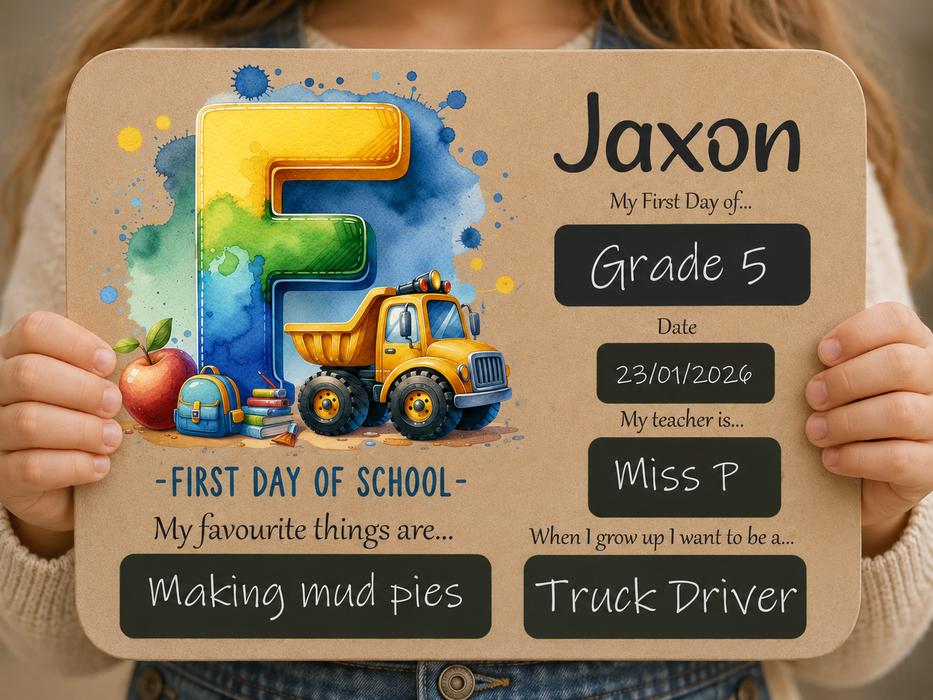 A child holds a personalized first-day-of-school sign with a large watercolor-style number 5, a yellow dump truck, an apple, books, and chalkboard-style text fields. The sign is centered against the child's torso, with hands visible holding it.
