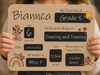 A child holds a personalized first-day-of-school sign personalised, Grade 5, and fill-in boxes for age, favorite things, date, height, teacher, and aspirations. The sign has a warm tan background with black text boxes and small orange, brown, and blue floral illustrations.