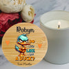 A round wooden coaster or plaque with a printed cartoon duck and the text 'Robyn do i look like i give a duck?' is shown on a marble surface next to a lit white candle and flowers.